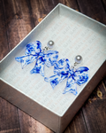 Blue floral chinoiserie acrylic bow earrings with pearl stud tops displayed in a premium white Slate & Ember jewelry gift box.