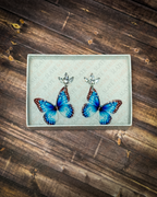 Blue butterfly acrylic earrings with crystal leaf stud tops displayed inside a premium white Slate & Ember jewelry gift box.