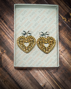 Laser-cut wooden filigree heart earrings with open scrollwork and silver bow stud tops displayed inside a white Slate & Ember jewelry gift box.