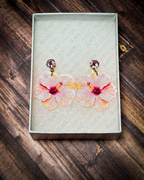 Pink watercolor hibiscus acrylic earrings with pink crystal gold stud tops displayed inside a premium white Slate & Ember jewelry gift box.
