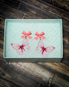 Pink watercolor butterfly acrylic earrings with pink bow stud tops displayed inside a premium white Slate & Ember jewelry gift box.